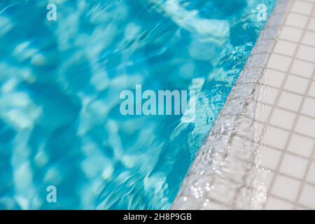 Oberfläche des blauen Swimmingpools. Sommer Wassersport, Freizeit Hintergrund. Textur der Wasseroberfläche, blau türkis lebhaft hell sonnig Nahaufnahme. Entspannen Sie Sich Stockfoto