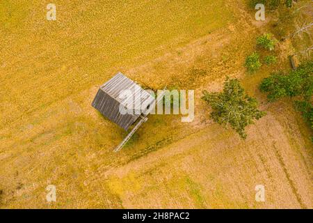 Alte Holzmühlenblätter aus der Nähe. Heller Himmel der untergehenden Sonne. Kleine Kreuzung im Hintergrund. Antenne Stockfoto