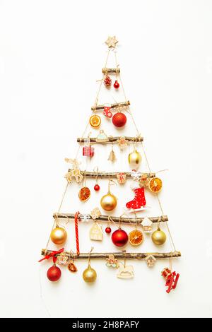 Handgefertigter Weihnachtsbaum hängt an einer weißen Wand. Alternative Dekoration, umweltfreundliche weihnachten, Bürgerbewusstsein. Stockfoto