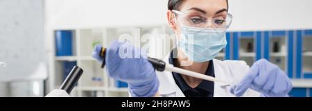 Wissenschaftler in medizinischen Maske und Latexhandschuhe arbeiten mit Pipette im Labor, Banner Stockfoto