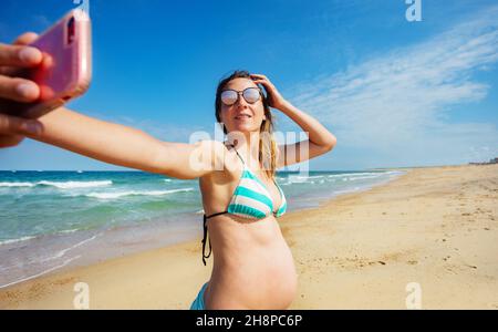 Eine Schwangerin fotografiert sie am Strand Stockfoto