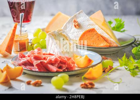 Schinken- und Käseplatte mit Trauben, Nüssen und Rotwein Stockfoto