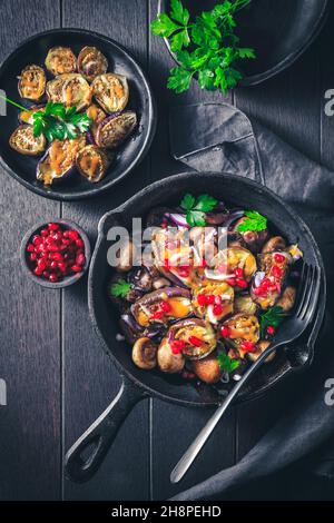 Gebackene kleine Auberginen, gefüllt mit Pilzen und Granatapfel in einer Backform Stockfoto