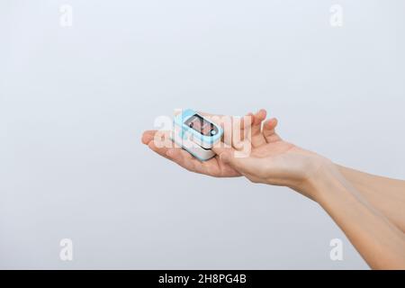 Pulsoximeter mit der Hand des Arztes auf Weiß isoliert. Messung der Sauerstoffsättigung, der Pulsfrequenz und des Sauerstoffgehalts. Das Konzept der tragbaren Digitaltechnik Stockfoto