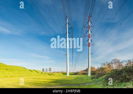 Landschaft mit modernen Hochspannungsmasten mit Kabeln in De Groene Weelde in Vijfhuizen in der Gemeinde Haarlemmermeer, Niederlande Stockfoto