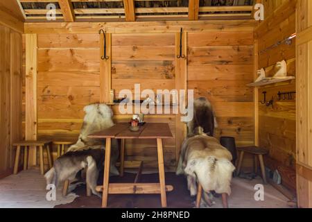 Gudvangen, Norwegen - ca. September 2021: Innenraum eines Wikingerhauses mit Pelzquilts auf Stühlen Stockfoto