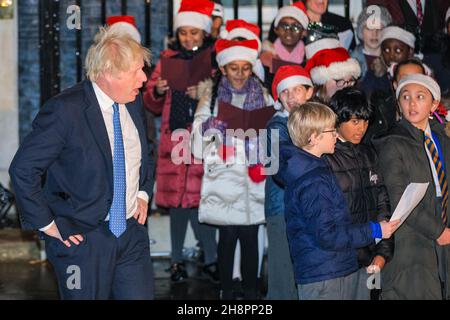 Westminster, London, Großbritannien. 01st Dez 2021. Der PM sieht den Kindern beim Singen zu. Premierminister Boris Johnson schaltet heute Abend vor der Downing Street 10 die offiziellen Christbaumlichter ein. Außerdem singt ein Kinderchor Weihnachtslieder und geladene Gäste sehen sich die Zeremonie an. Kredit: Imageplotter/Alamy Live Nachrichten Stockfoto