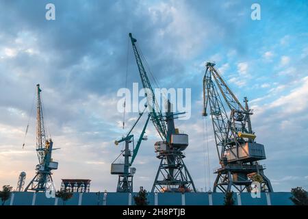 Hafenkrane aus der Nähe vor einem wunderschönen blauen Himmel mit Wolken vor Sonnenuntergang. Frachtterminal. Batumi, Georgia Stockfoto