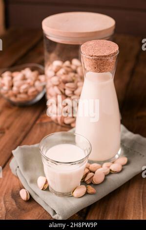 Frische, hausgemachte Pistazien-Milch in einer transparenten Flasche und Pistazien. Vegetarische Alternative zur Milch. Konzept der laktosefreien Produkte und Diät-Lebensmittel. Hochwertige Fotos Stockfoto