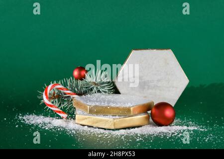 Marmorpult mit sechseckigen Elementen und Dekor für Weihnachtsferien im Winter. Rote weiße Kugeln, Beeren auf Tannenzweigen, Zuckerrohr. Stockfoto