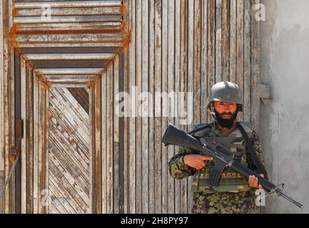 Ein Soldat der afghanischen Nationalen Sicherheitskräfte steht am 1. April 2011 bei einer Zeremonie zum Schneiden von Bändern für eine Moschee im Arghandab-Flusstal in Tarok Kolache, Afghanistan, Wache. Das Dorf wurde aus Trümmern wieder aufgebaut, nachdem die Koalitionsbomben die Siedlung im Jahr 2010 abgeflacht hatten. Stockfoto