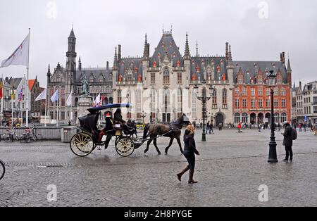 Das historische Zentrum von Brügge in Belgien mit einer Pferdekutsche, mit der Touristen auf Stadtrundfahrten durch die Stadt gebracht werden, führt durch den Burgplatz vor dem Hotel Stockfoto