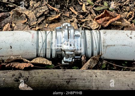 Anschluss von Rohren zum Pumpen von Wasser aus dem Teich mit einer Kupplung und einem Draht. Im Laufe der Zeit rostet der Draht und die Rohre laufen aus. Stockfoto