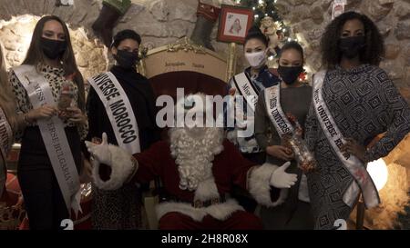 Jerusalem, Israel. 1st Dez 2021. Miss Universe-Teilnehmer posieren für ein Bild mit Jerusalems Weihnachtsmann als Teilnehmer der Miss Universe-Parade durch die Altstadt am 01. Dezember 2021 in Jerusalem, Israel. Der Miss Universe Wettbewerb 70th wird trotz Reisebeschränkungen aufgrund der Omicron-Coronavirus-Variante im israelischen Ferienort Eilat am Roten Meer stattfinden. Kredit: Eddie Gerald/Alamy Live Nachrichten Stockfoto