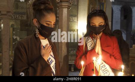 Jerusalem, Israel. 1st Dez 2021. Miss Cayman Islands Georgina Kerford und Miss Armenien Mirna Bzdigian zünden Kerzen an und betet in der Grabeskirche, als Teilnehmer des Miss Universe-Festzugs am 01. Dezember 2021 in Jerusalem, Israel, durch die Altstadt. Der Miss Universe Wettbewerb 70th wird trotz Reisebeschränkungen aufgrund der Omicron-Coronavirus-Variante im israelischen Ferienort Eilat am Roten Meer stattfinden. Kredit: Eddie Gerald/Alamy Live Nachrichten Stockfoto