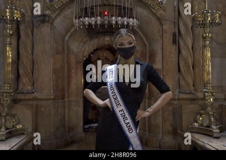 Jerusalem, Israel. 1st Dez 2021. Miss Finnland Essi Unkuri posiert für ein Bild neben dem Grab Jesu in der Grabeskirche als Teilnehmer des Miss Universe-Festzugs am 01. Dezember 2021 in Jerusalem, Israel, durch die Altstadt. Der Miss Universe Wettbewerb 70th wird trotz Reisebeschränkungen aufgrund der Omicron-Coronavirus-Variante im israelischen Ferienort Eilat am Roten Meer stattfinden. Kredit: Eddie Gerald/Alamy Live Nachrichten Stockfoto