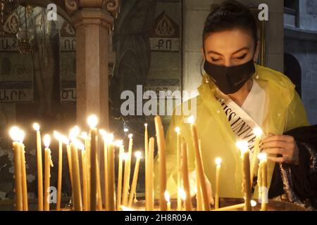 Jerusalem, Israel. 1st Dez 2021. Miss Albanien Ina Dajci zündet Kerzen in der Grabeskirche an, als Teilnehmer des Miss Universe-Festzugs am 01. Dezember 2021 in Jerusalem, Israel, die Altstadt bereisen. Der Miss Universe Wettbewerb 70th wird trotz Reisebeschränkungen aufgrund der Omicron-Coronavirus-Variante im israelischen Ferienort Eilat am Roten Meer stattfinden. Kredit: Eddie Gerald/Alamy Live Nachrichten Stockfoto