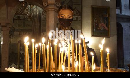 Jerusalem, Israel. 1st Dez 2021. Miss Finnland Essi Unkuri zündet Kerzen in der Grabeskirche an, als Teilnehmer des Miss Universe-Festzugs am 01. Dezember 2021 in Jerusalem, Israel, die Altstadt bereisen. Der Miss Universe Wettbewerb 70th wird trotz Reisebeschränkungen aufgrund der Omicron-Coronavirus-Variante im israelischen Ferienort Eilat am Roten Meer stattfinden. Kredit: Eddie Gerald/Alamy Live Nachrichten Stockfoto