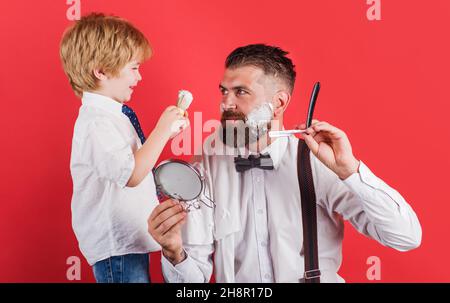 Kleiner Barbier. Salon für Männer. Assistent für Papa. Barbershop-Konzept. Rasieren des Bartes im Friseurladen. Stockfoto