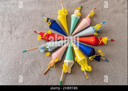 Zwölf bunte kleine gefüllte Zuckerzapfen für den Schulrückgang, die in einem Kreis auf grauem Hintergrund angeordnet sind Stockfoto