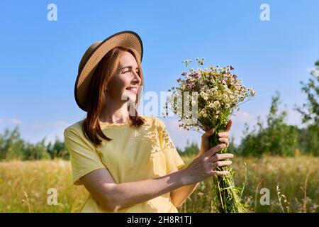Schöne glückliche Erwachsene Frau mit Blumenstrauß auf der Sommerwiese Stockfoto