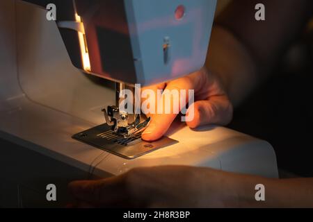 Die Hände der Frau nähen auf einer Nähmaschine, Nahaufnahme, Arbeitsprozess Stockfoto