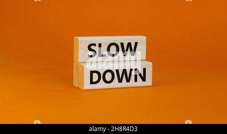 Zeit zum Verlangsamen des Symbols. Konzeptwörter verlangsamen sich auf Holzblöcken auf einem schönen orangefarbenen Hintergrund. Business und Slow-Down-Konzept. Speicherplatz kopieren. Stockfoto