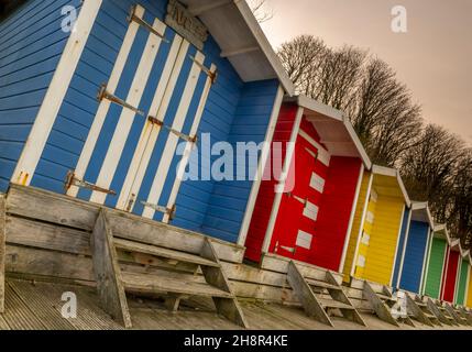 Reihe von bunten Strandhütten an der Küste der Isle of Wight, Reihe von Strandhütten, terrassenförmige Strandhütten an der Küste der Isle of Wight, anders, ungewöhnlich Stockfoto