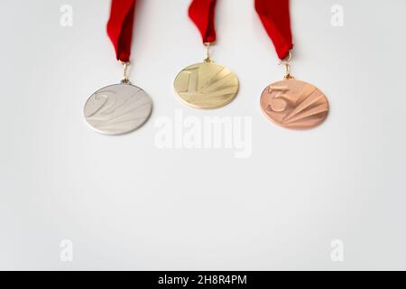 Gold-, Silber- und Bronzemedaillen mit Zahlen auf weißem, isoliertem Hintergrund für Sieger.Medaille mit roten Bändern. Stockfoto