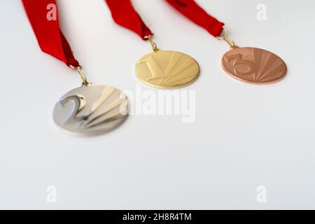 Gold-, Silber- und Bronzemedaillen mit Zahlen auf weißem, isoliertem Hintergrund für Sieger.Medaille mit roten Bändern. Stockfoto