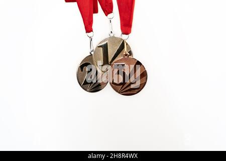 Gold-, Silber- und Bronzemedaillen mit Zahlen auf weißem, isoliertem Hintergrund für Sieger.Medaille mit roten Bändern. Stockfoto