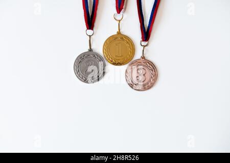 Gold-, Silber- und Bronzemedaillen mit Zahlen auf weißem, isoliertem Hintergrund für Sieger.Medaille mit roten Bändern. Stockfoto