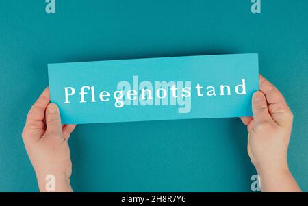 Das Wort Pflegehotstand steht in deutscher Sprache auf einem blau gefärbten Papier Stockfoto