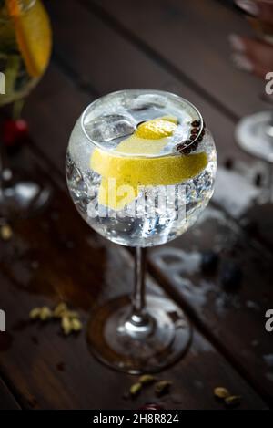 Bebida alcohólica (trago de Gin and Tonic) con Limón y histo en Rústica mesa de madera mojada. Stockfoto