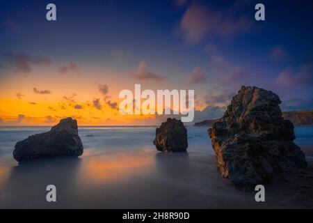 Seascape von drei Felsbrocken am Strand mit Blick auf den Sonnenuntergang in Sonoma County, Kalifornien. Langzeitbelichtung, blau und orange. Düster, friedlich. Bewölkt. Stockfoto