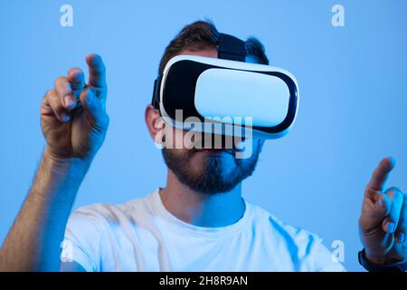 Nahaufnahme eines hübschen Mannes, der Videospiele in 3D Gläsern spielt. Der Spieler trägt ein Virtual-Reality-Headset für ein Smartphone auf dem Kopf und lächelt. Stockfoto