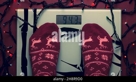 Gewichtskontrolle mit Badwaage nach der Weihnachtszeit. Die Frau wurde während des Winters dick. Fuß auf einer Skala Stockfoto