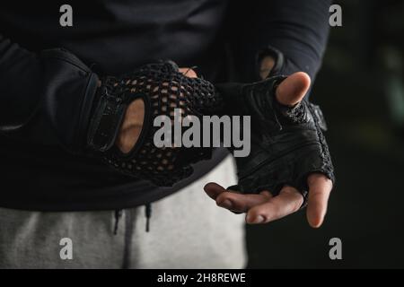 Nahaufnahme der Hände eines unbekannten kaukasischen Mannes, der Turnhandschuhe auszieht oder auszieht Stockfoto