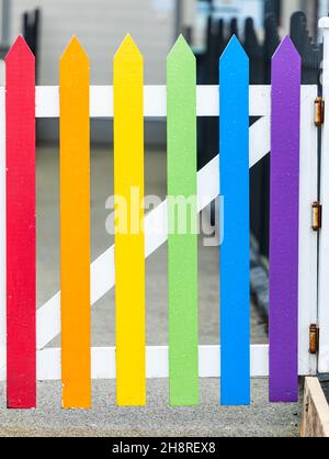 Nahaufnahme eines regenbogenfarbenen hölzernen Zauntores in einer kleinen Stadt. Stockfoto