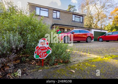 „Santa please stop here“ – festliches Novum-Zeichen für Weihnachten in einem Vorgarten vor einem Haus in Surrey im Dezember Stockfoto