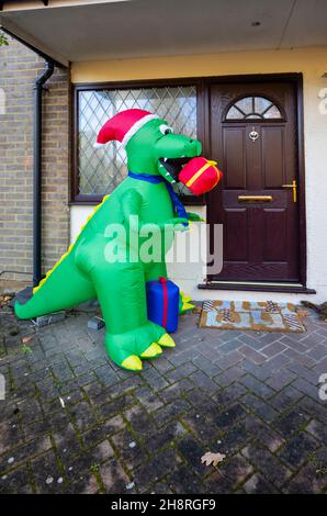Große grüne Neuheit Kunststoff Blow-up festliche Dinosaurier vor einem Haus in Surrey in der Weihnachtszeit im Dezember Stockfoto