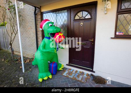 Große grüne Neuheit Kunststoff Blow-up festliche Dinosaurier vor einem Haus in Surrey in der Weihnachtszeit im Dezember Stockfoto