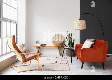 Moderne Bank mit Pouf, Kissen und Holzhand im Inneren des hellen Wohnzimmers Stockfoto