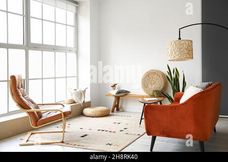 Moderne Bank mit Pouf, Kissen und Holzhand im Inneren des hellen Wohnzimmers Stockfoto