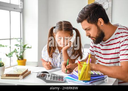 Mann hilft seiner kleinen Tochter, zu Hause Unterricht zu machen Stockfoto