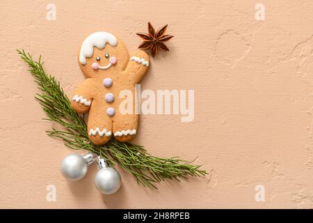 Komposition mit leckerem Lebkuchenmann, Nadelzweigen und Weihnachtskugeln auf farbigem Hintergrund Stockfoto