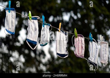 Covid-19 hausgemachte Gesichtsmasken trocknen nach dem Waschen auf Leinenlinie Stockfoto