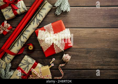 Weihnachtsgeschenkschachteln und Geschenkpapier auf rustikalem Holztisch. Flach liegend, Draufsicht, Overhead Stockfoto