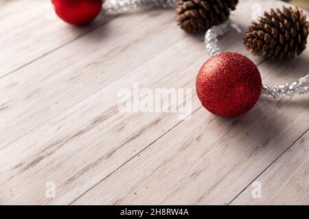 Tannenzapfen und rote weihnachtskugeln zur weihnachtsdekoration auf rustikalem weißen Holzhintergrund. Kopieren Sie Platz für Ihren Text Stockfoto