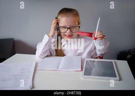 Ein kleines Mädchen, eine Geschäftsfrau, arbeitet zu Hause aus der Ferne, in Quarantäne, unterrichtet, trainiert. Stockfoto